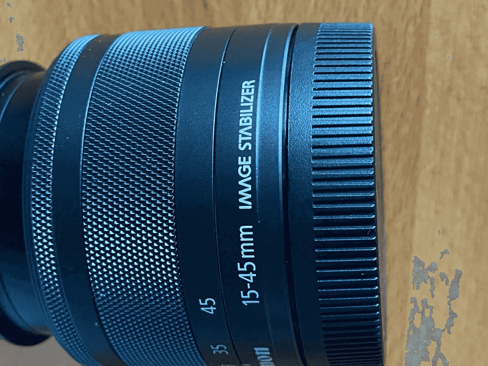 Primer plano de un objetivo con anillos y texto: 15-45 mm Estabilizador de Imagen.