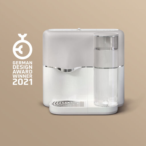 Ein weißer Wasserspender mit einem Glas gefüllt mit Wasser und einem Siegel 'German Design Award Winner 2021'.