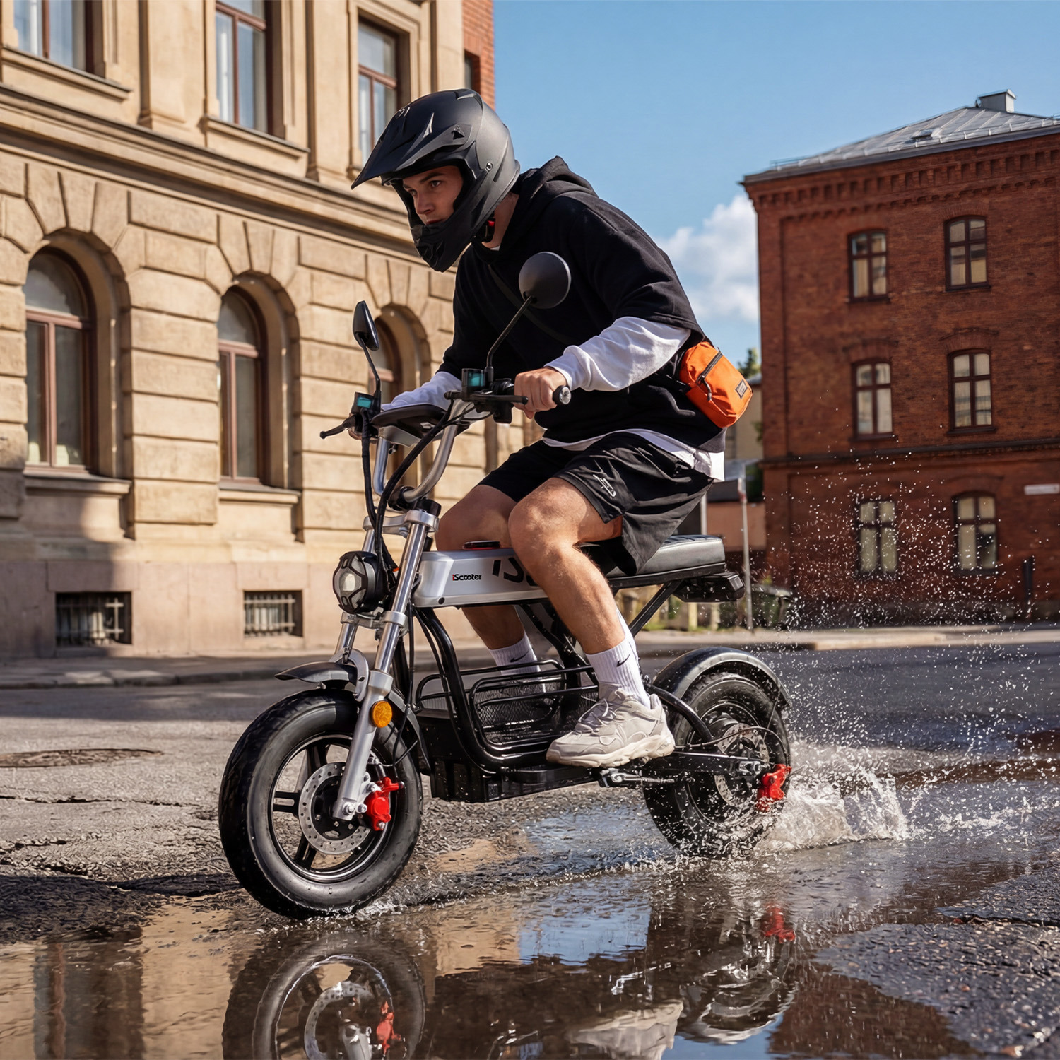 Un hombre monta en scooter a través del agua en una calle.