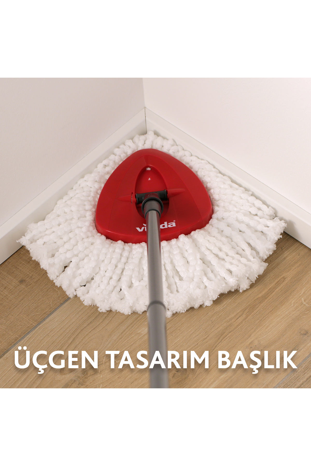 Ein roter Mop mit weißem Wischkopf in einer Ecke auf Holzboden.