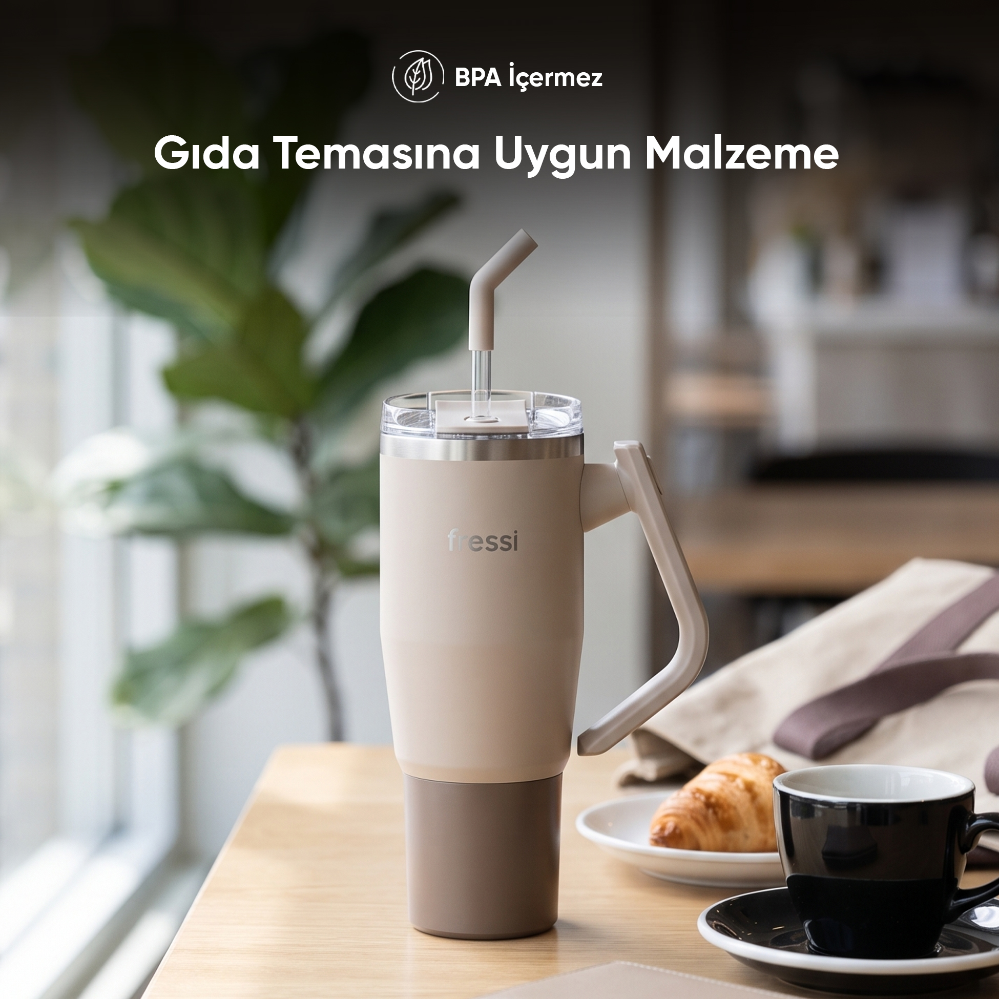 Pipetli bej seyahat kupası, kruvasan ve kahve ile masada duruyor.