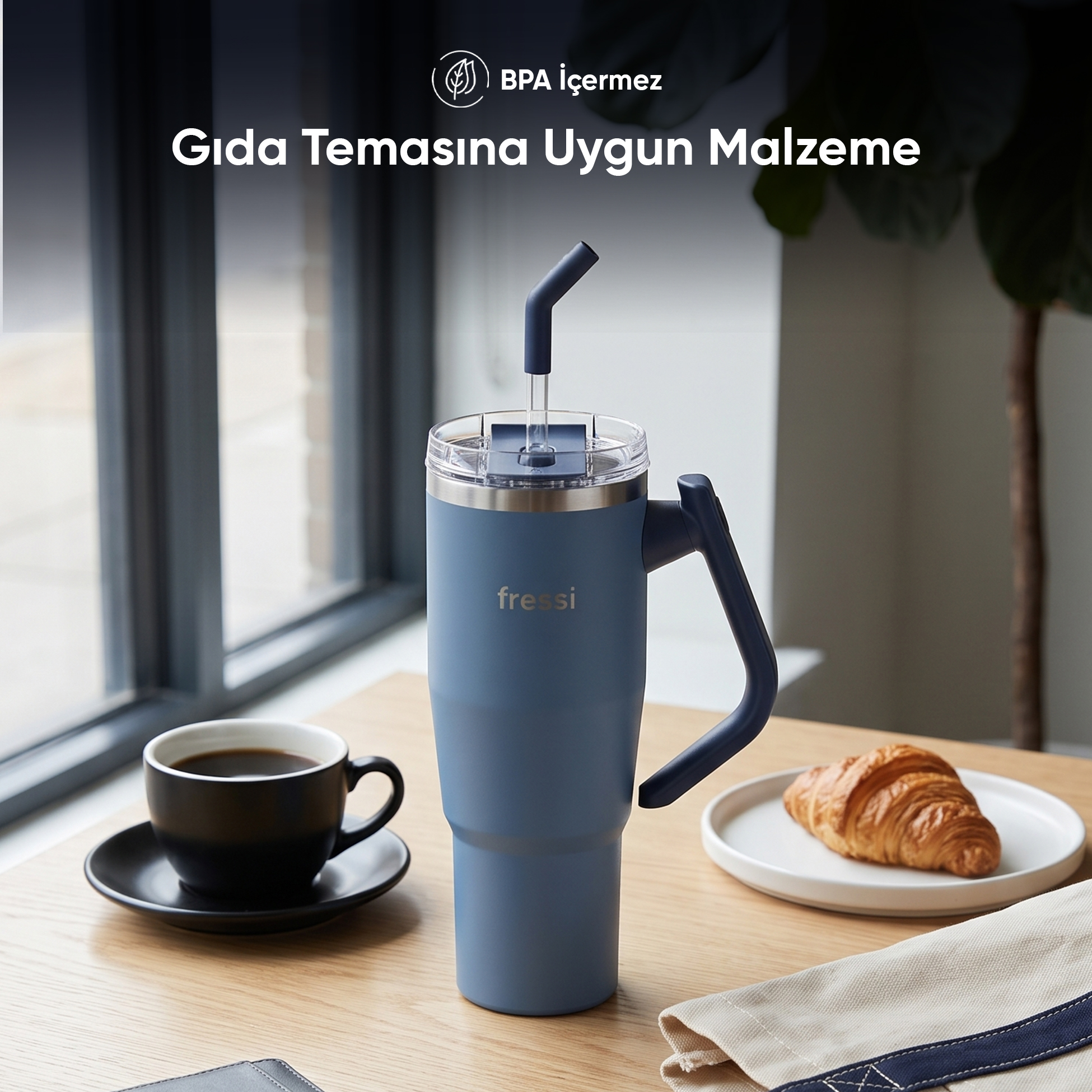 Kulplu mavi termos bardak, pipet, kahve ve masa üzerinde kruvasan.
