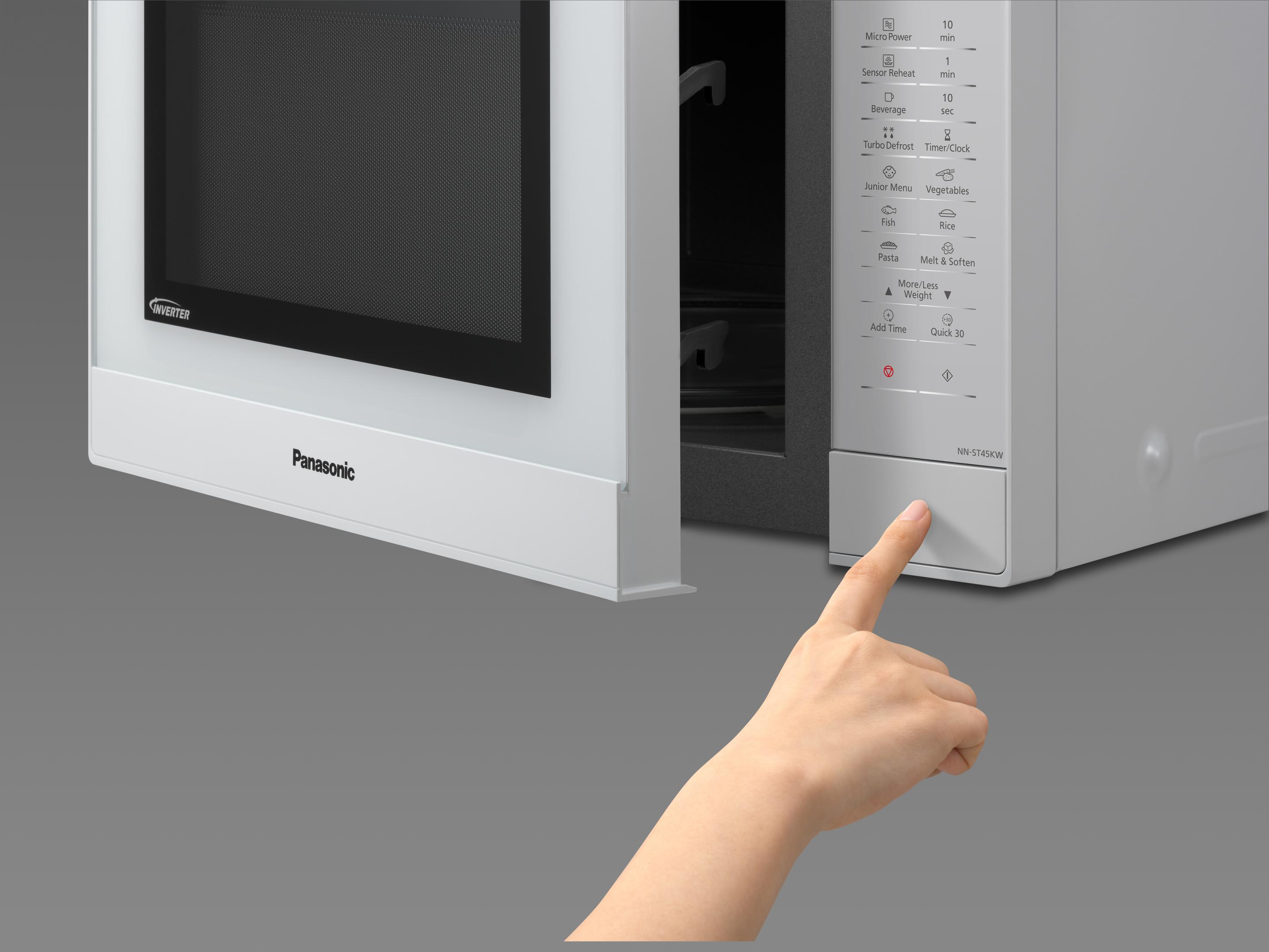 Un dedo presiona un botón en un microondas Panasonic blanco con puerta negra.