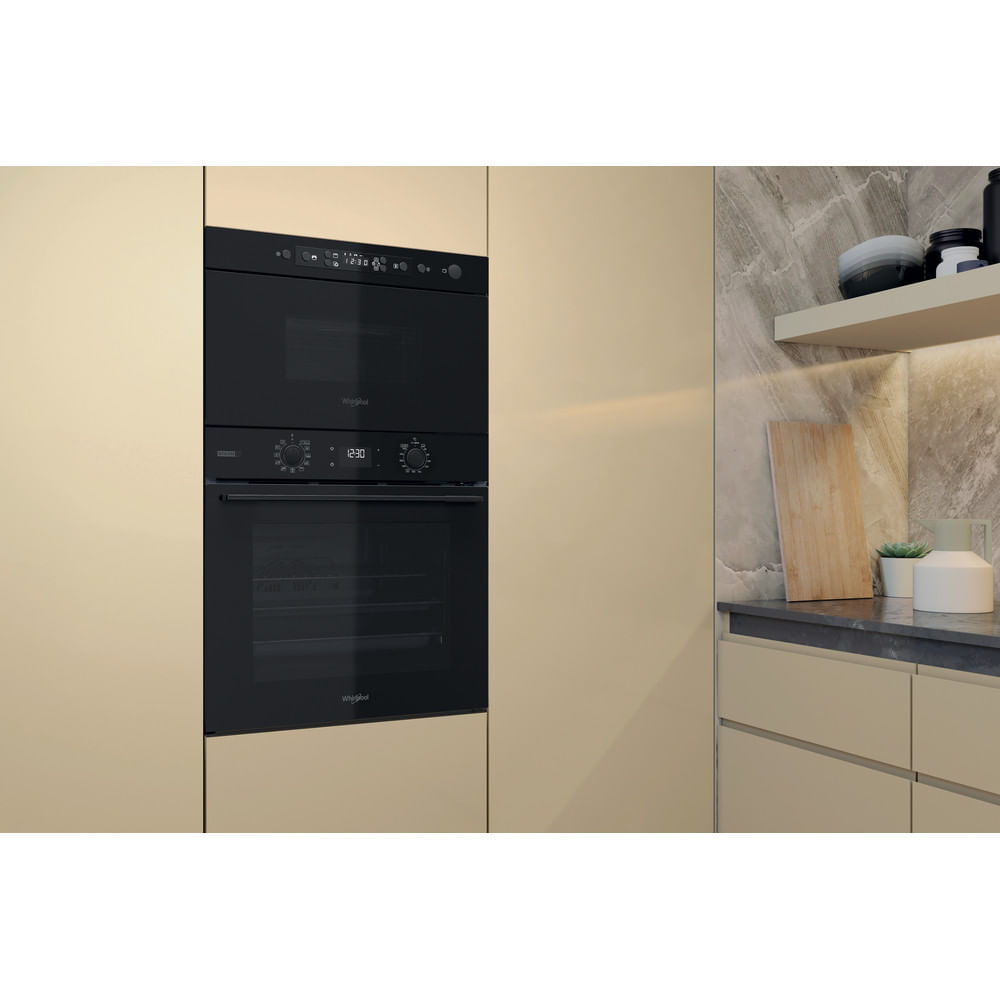 Un forno e microonde da incasso neri moderni in una credenza color crema.