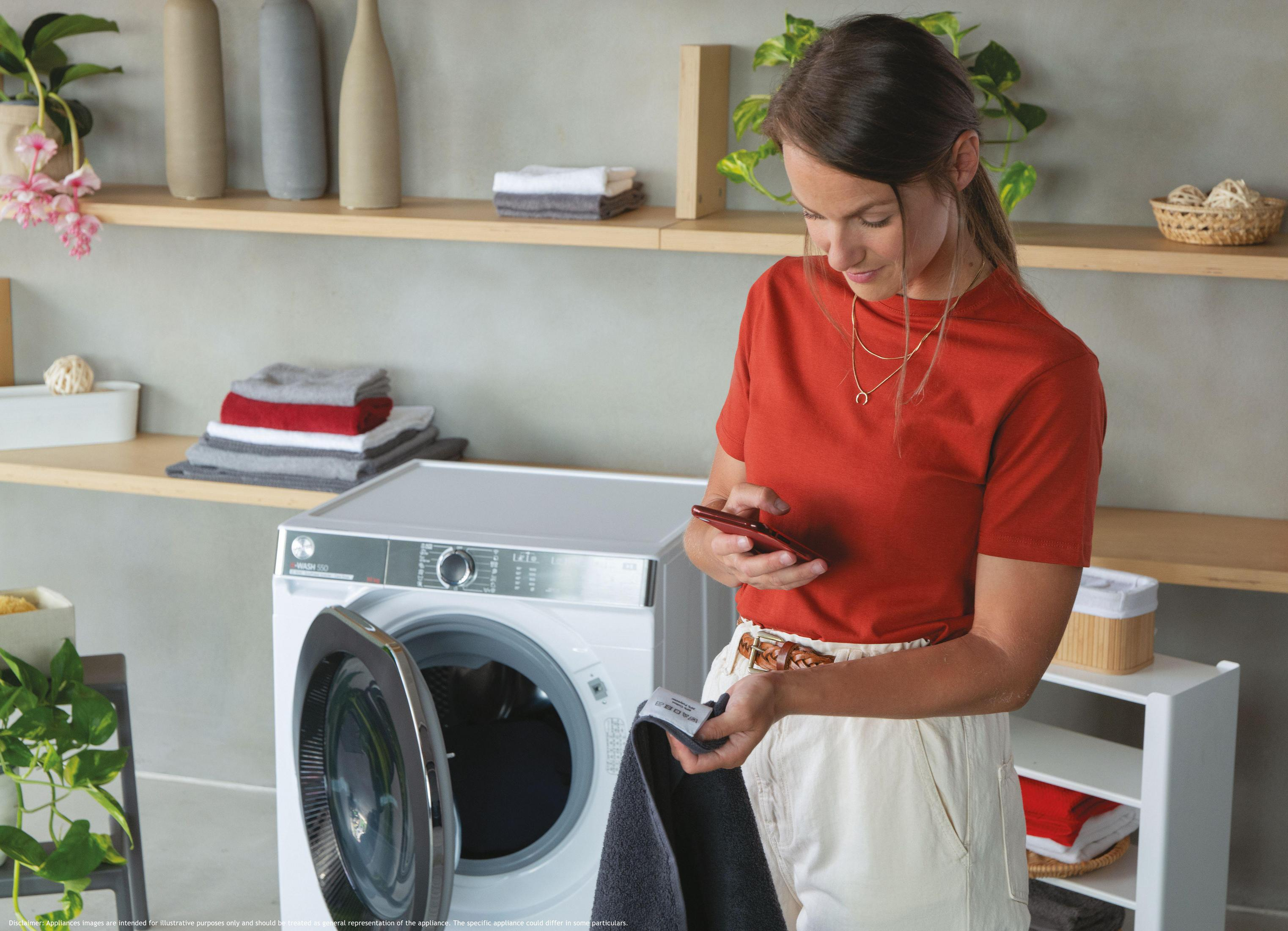 Una donna con maglia rossa tiene un telefono e un asciugamano grigio scuro.