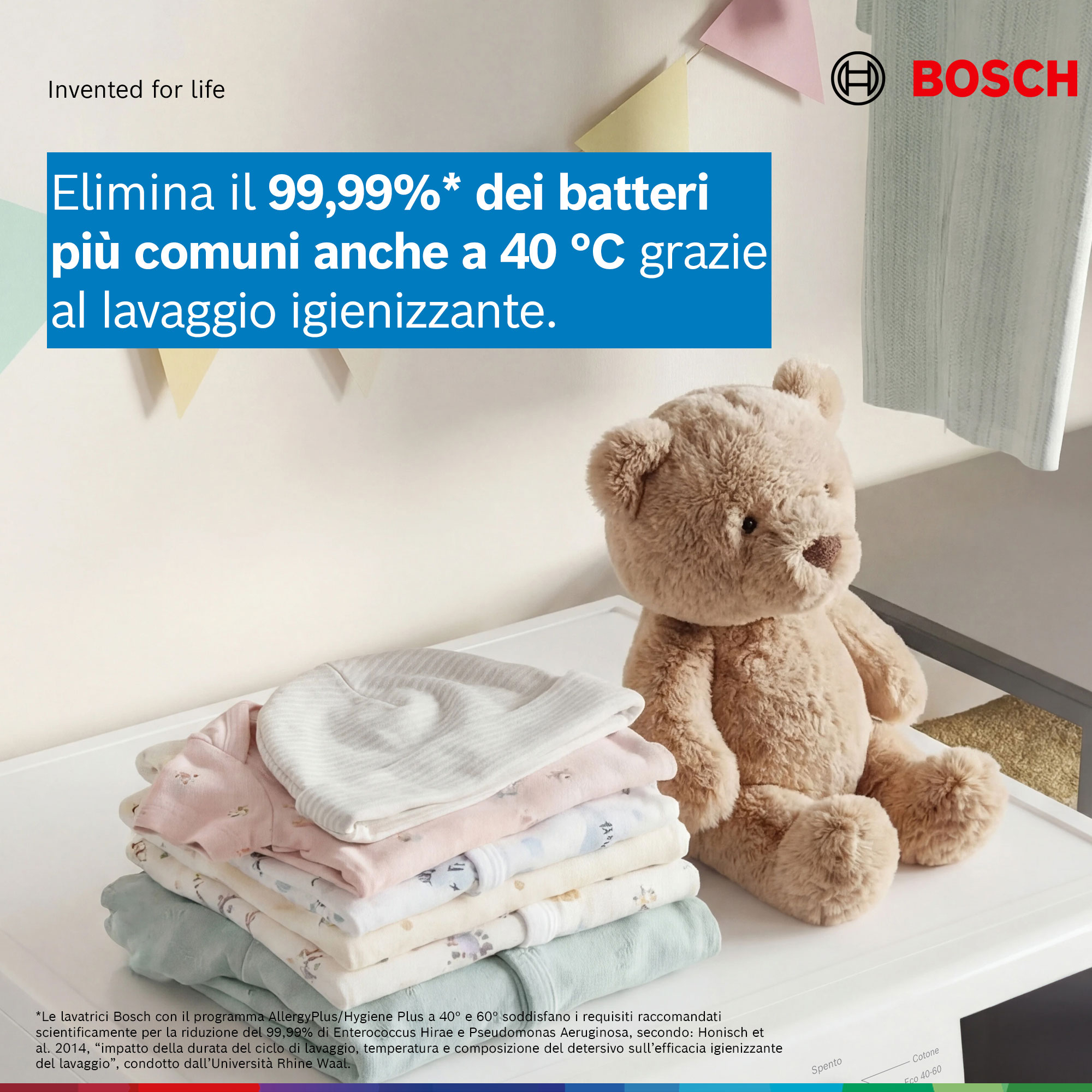 Un orsacchiotto accanto a una pila di vestiti per bambini davanti a una lavatrice Bosch.