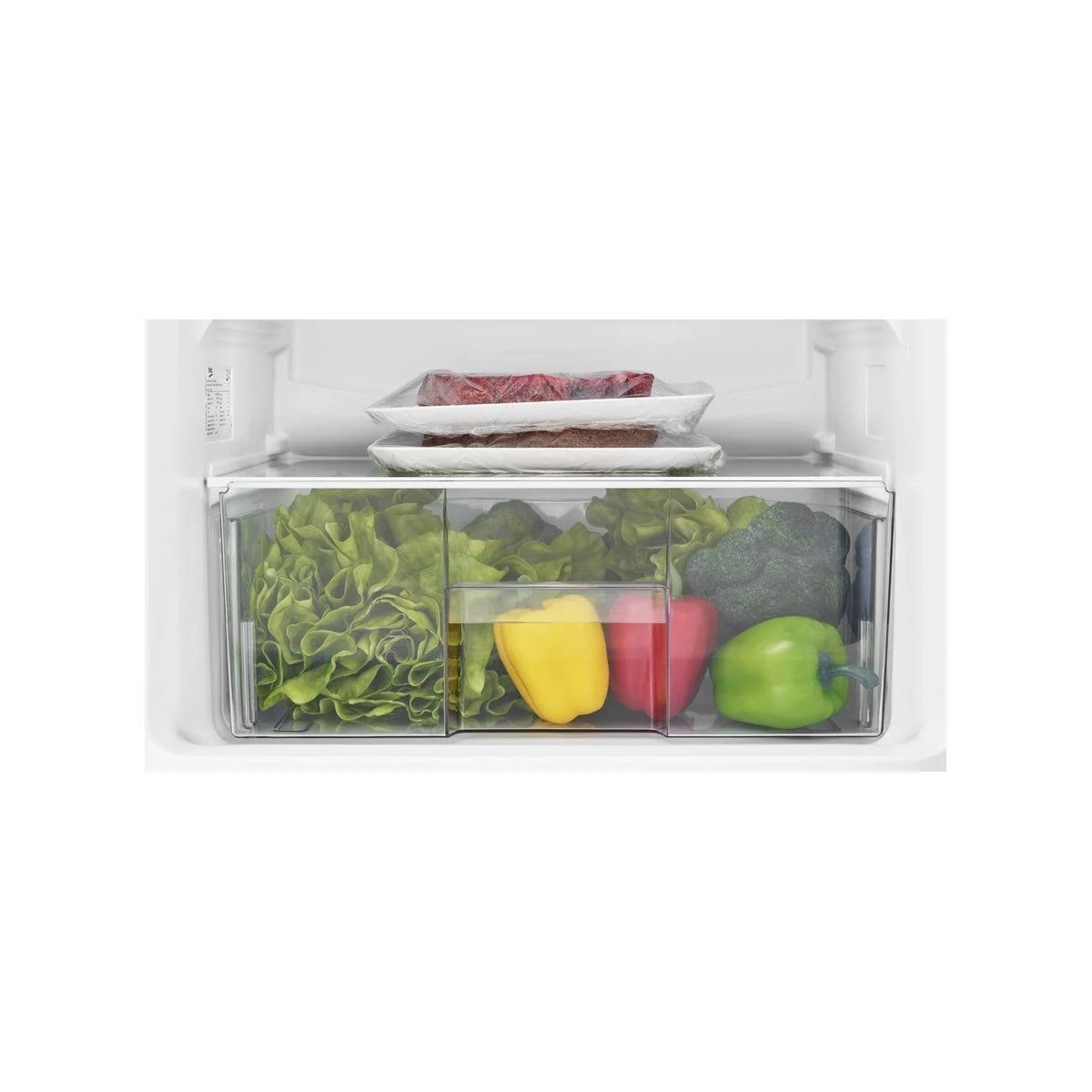 Dentro un cassetto del frigorifero: lattuga, peperoni, broccoli e confezioni di carne.