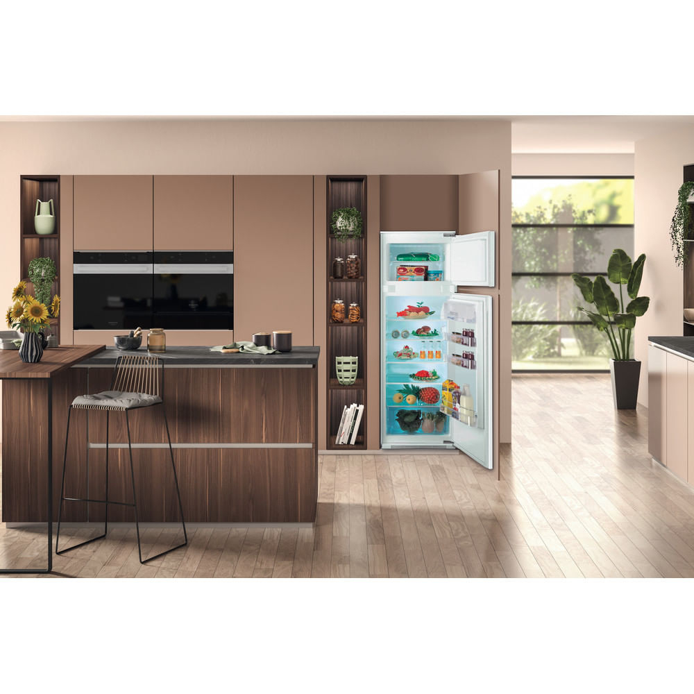 Cucina moderna con frigorifero aperto pieno di cibo, isola e forni.