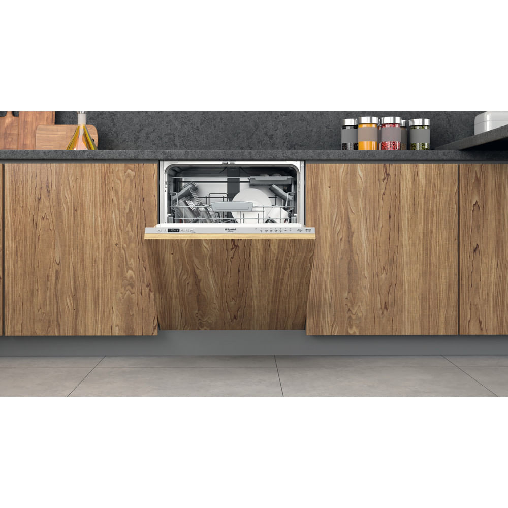 Lavastoviglie da incasso con porta aperta, mobili in legno, barattoli di spezie.