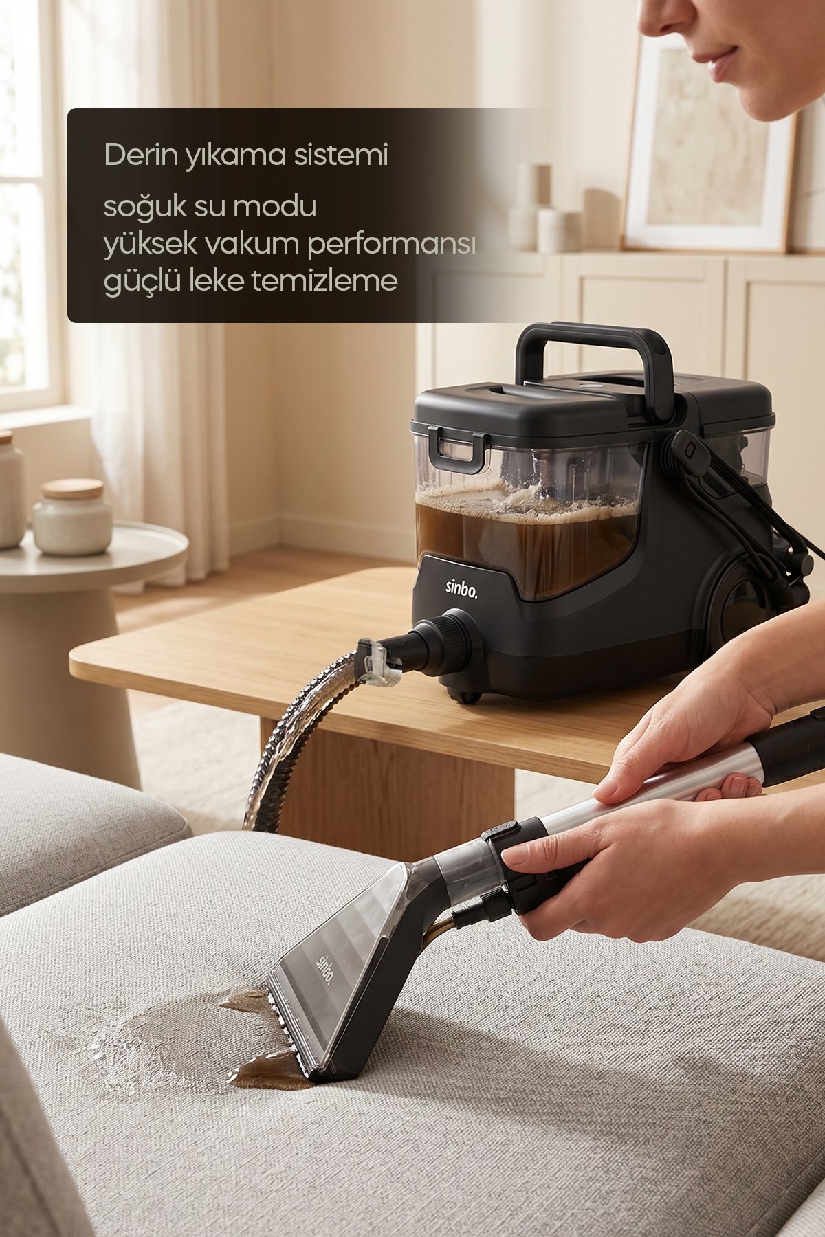 Bir kişi gri kumaş koltuk temizlemek için siyah ıslak/kuru vakum kullanıyor.