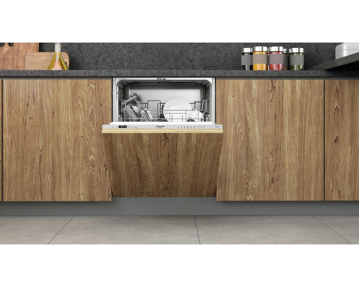 Una lavastoviglie da incasso con porta aperta in una cucina in legno.