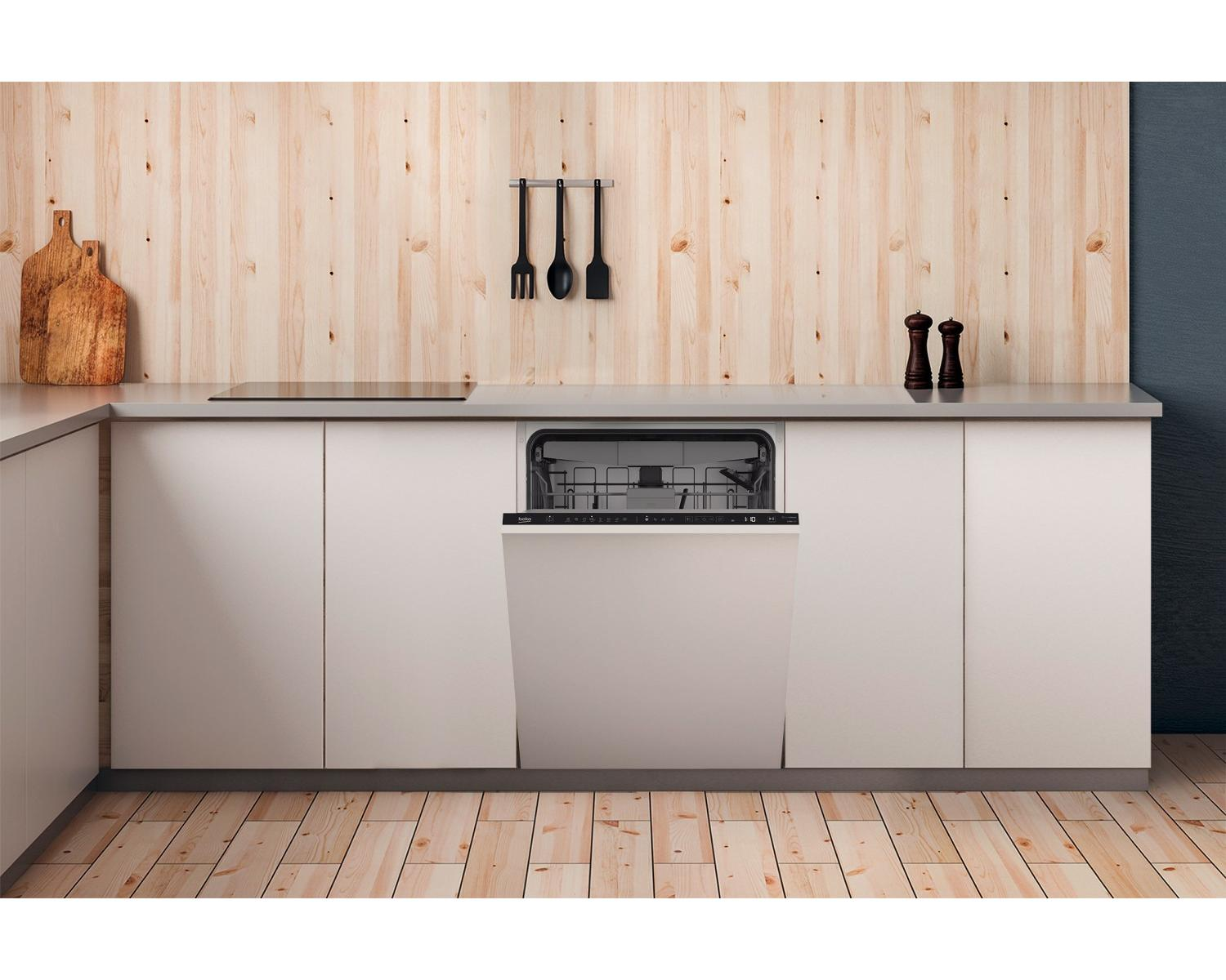Una lavastoviglie da incasso bianca con la porta aperta in una cucina con parete in legno.