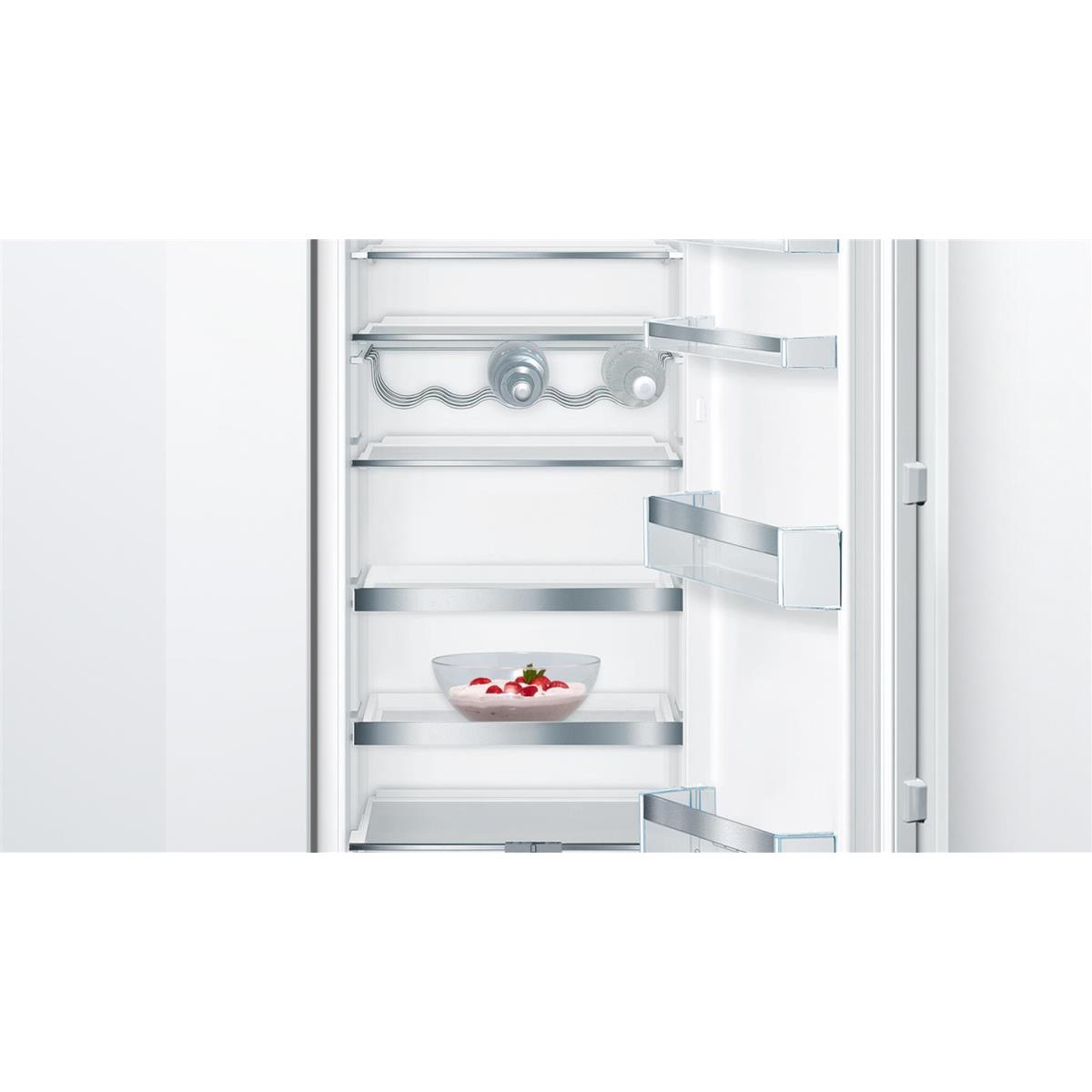 Refrigerador abierto con estantes de vidrio y un tazón de fresas en yogur.