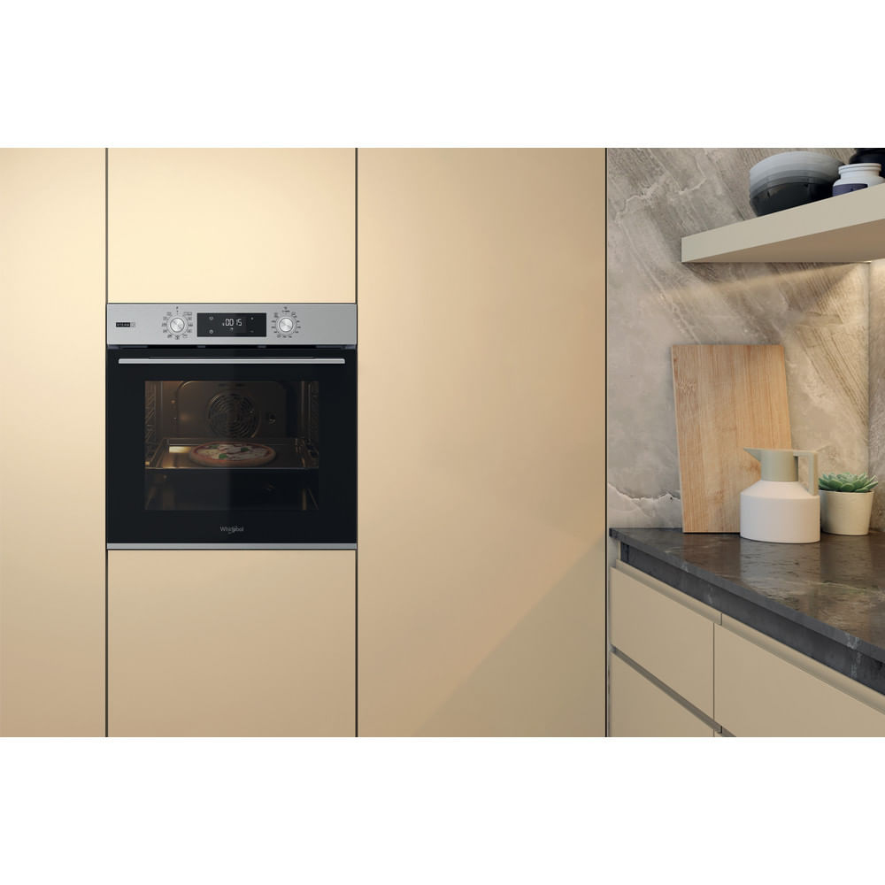 Forno da incasso moderno con pizza all'interno, accanto a un piano di lavoro decorato.