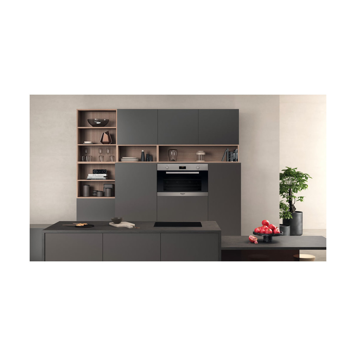Moderna cucina grigia con forno da incasso, mensole e ciotola di frutta.