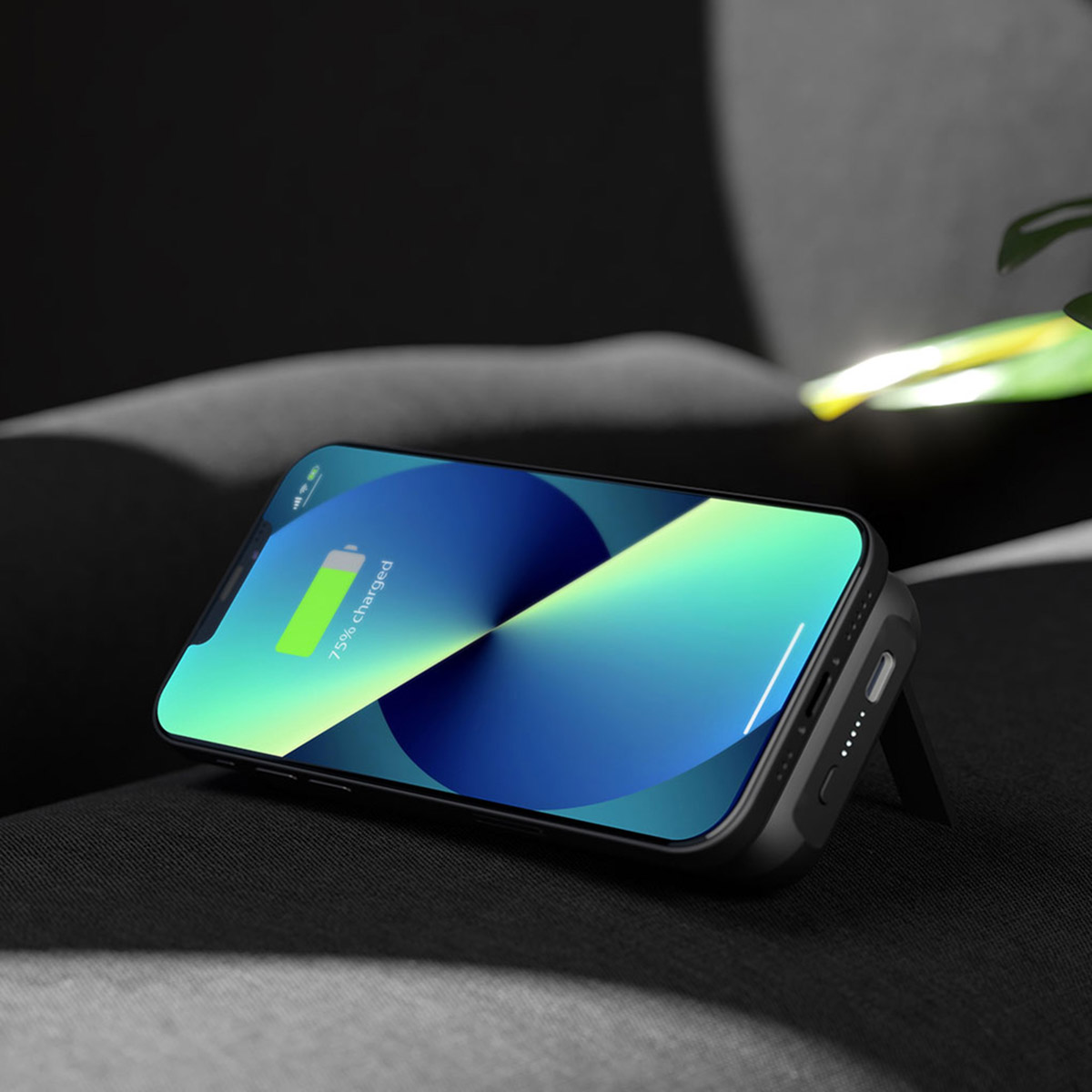 iPhone nero con batteria carica su tessuto scuro, appoggiato.