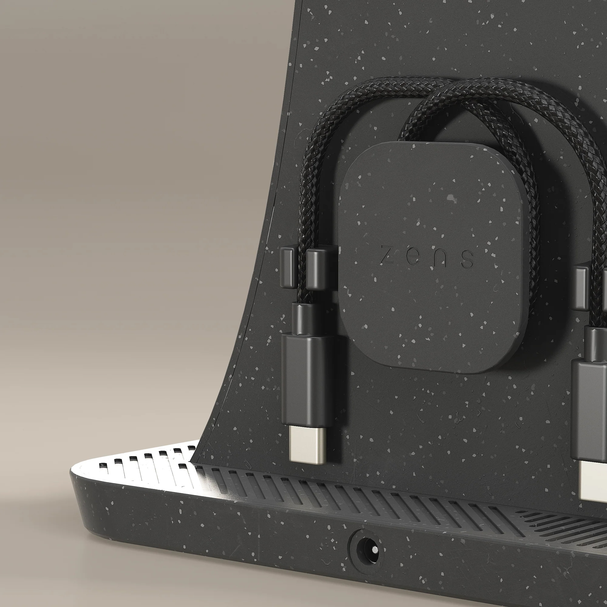 Eine schwarze gesprenkelte Ladestation mit zwei geflochtenen schwarzen Kabeln und USB-C-Anschlüssen.