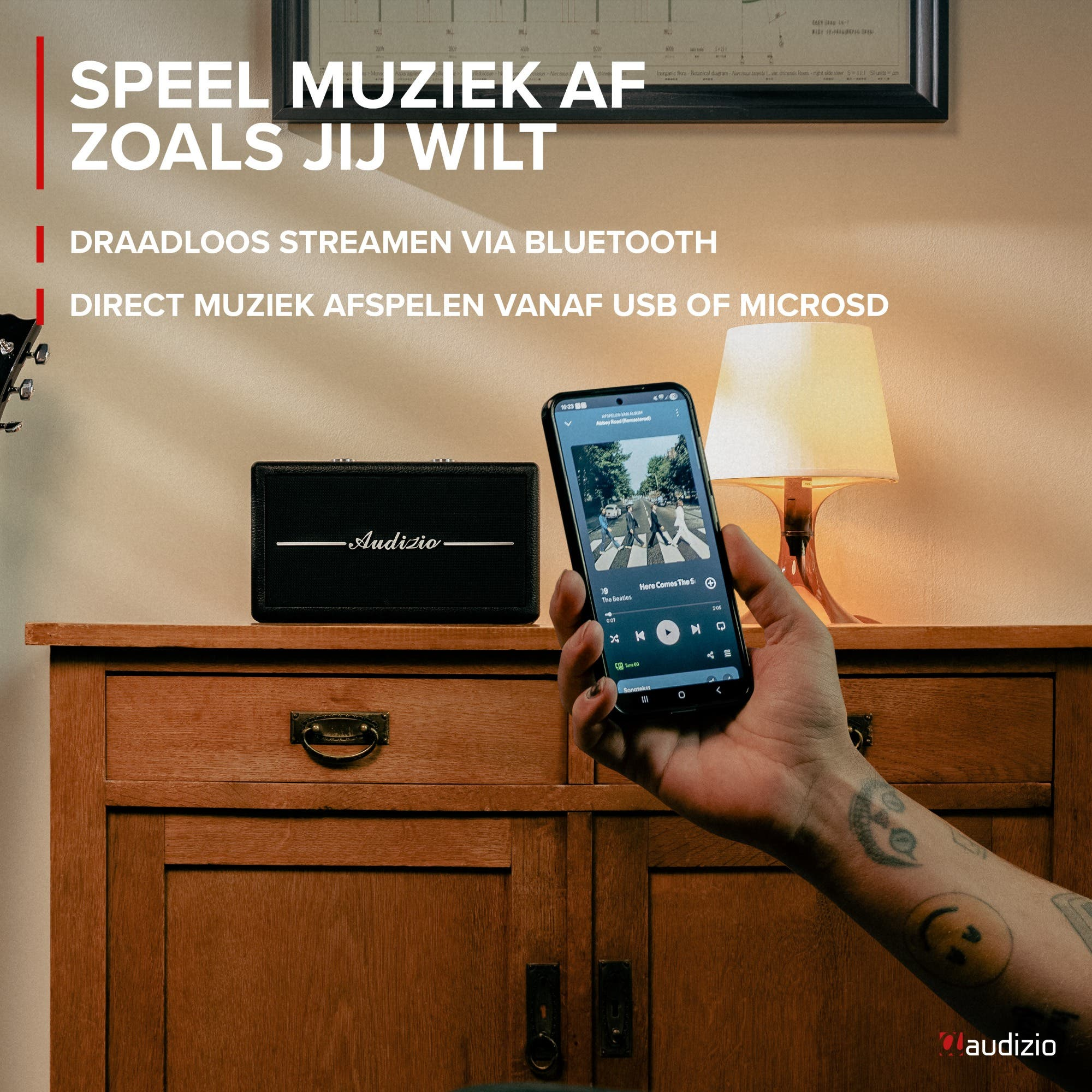 Un teléfono muestra reproducción de música junto a un altavoz. Una persona sostiene el teléfono.