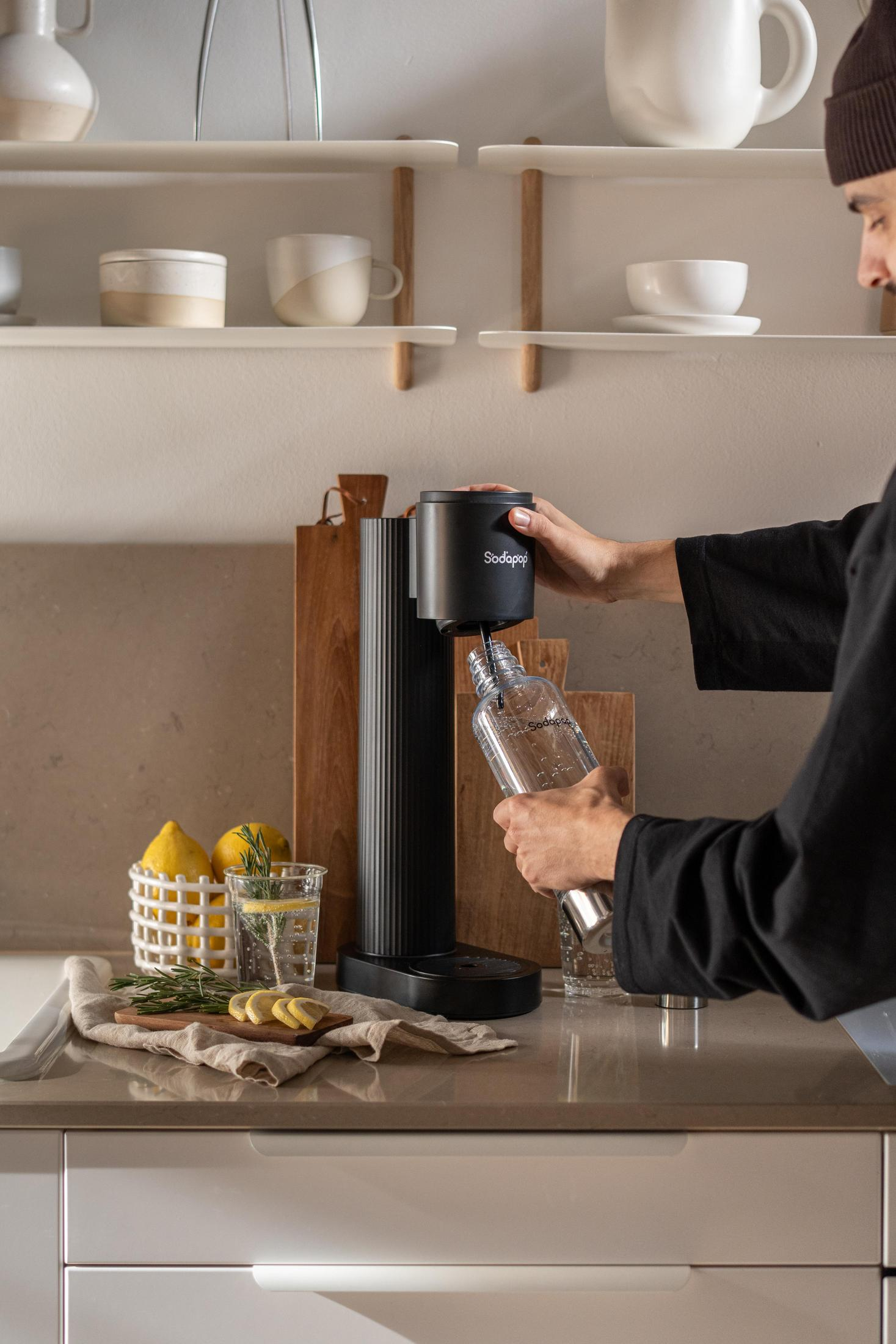 Persona che prepara acqua frizzante con un dispositivo Sodastream.