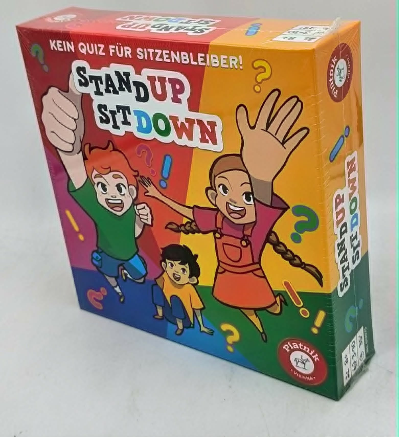 Kartenspielverpackung mit bunten Comicfiguren, Spieltitel 'Stand Up Sit Down'.