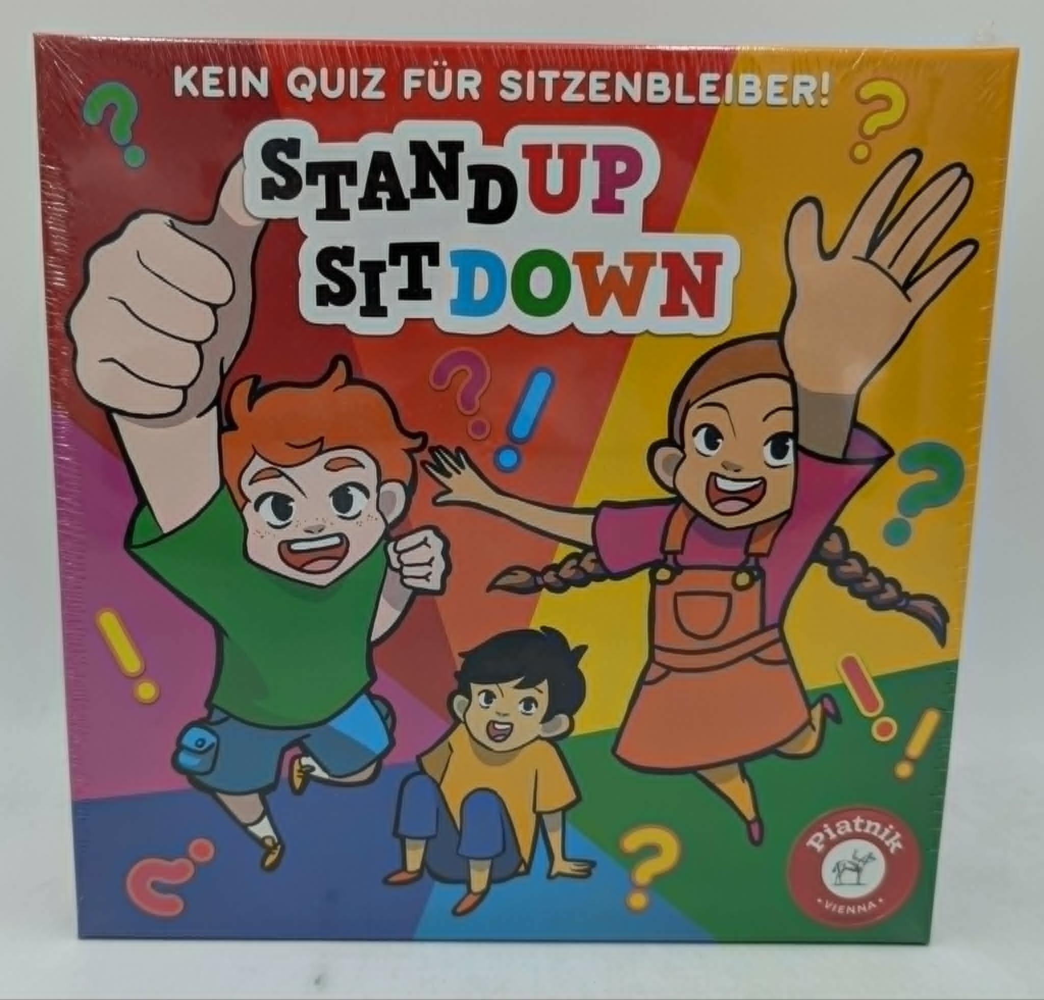 Brettspielpackung mit Kindern, die spielen. "Stand Up Sit Down" ist auf Deutsch.