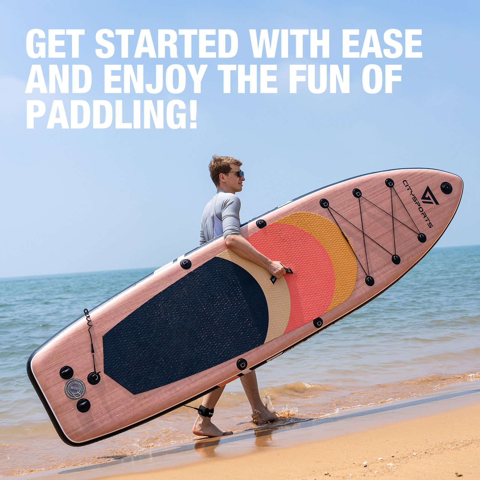 Een man draagt een roze paddleboard op het strand.