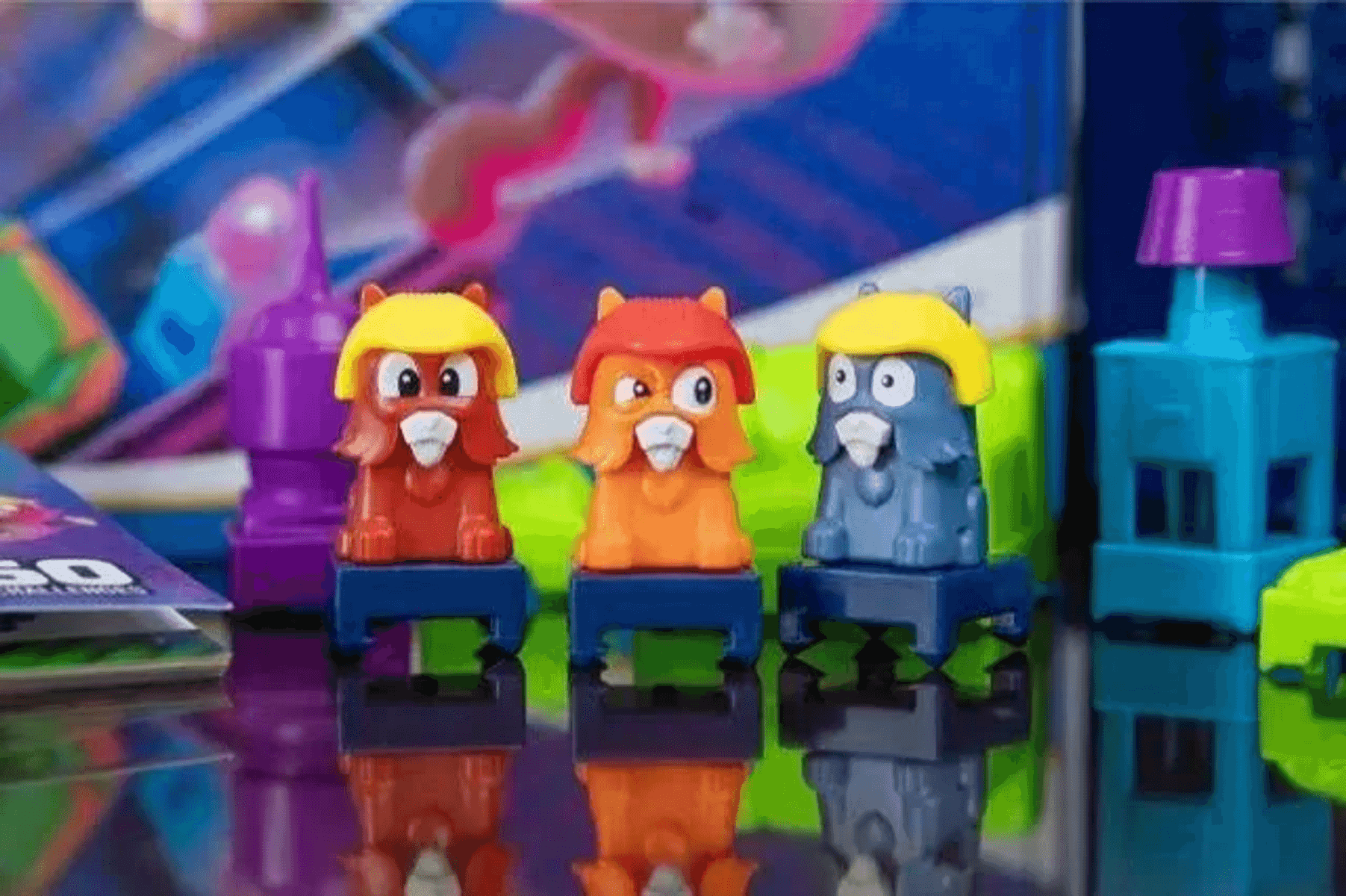 Trois figurines jaunes casquées se tiennent côte à côte sur des socles bleus.