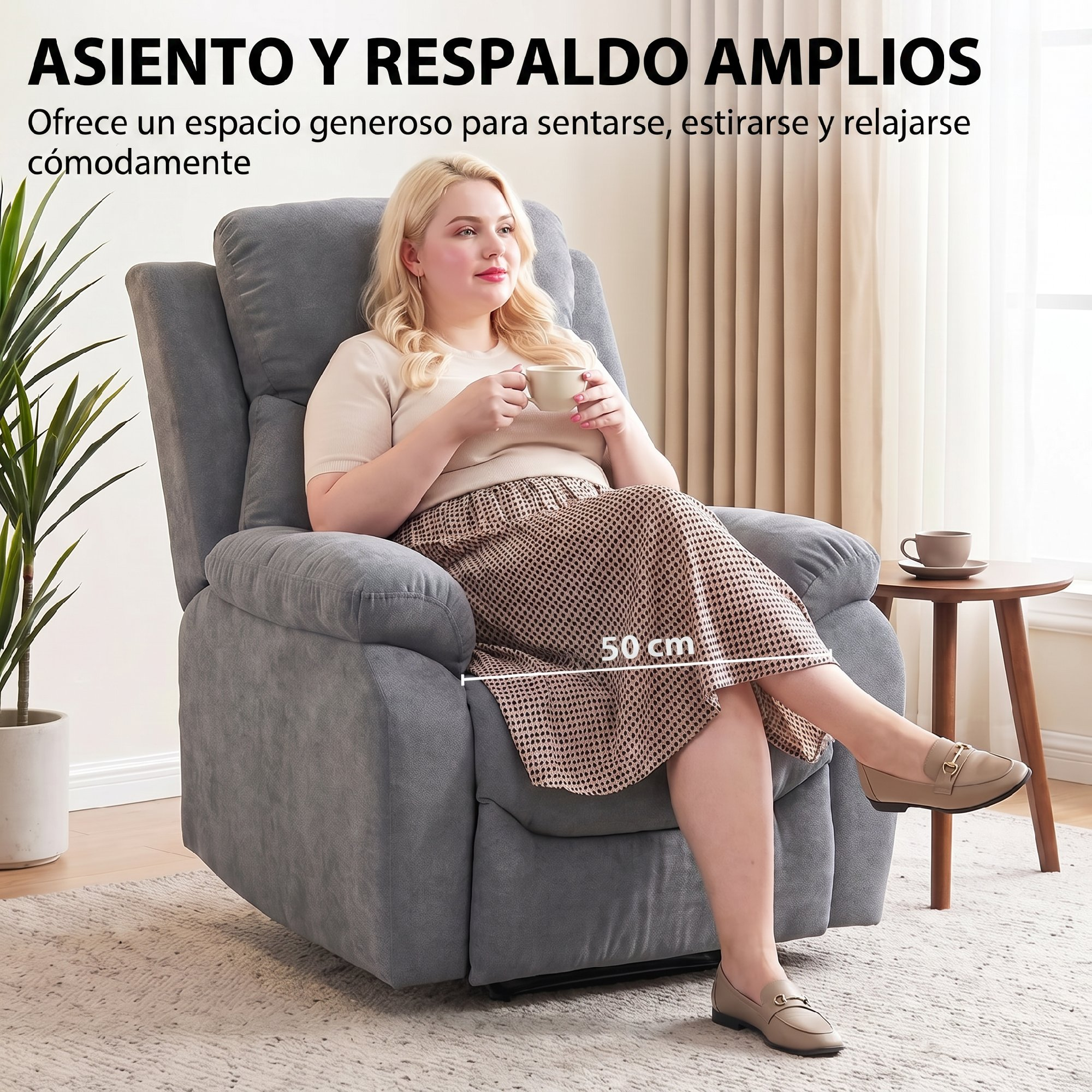 Una mujer sentada en un sillón gris, sosteniendo una taza.