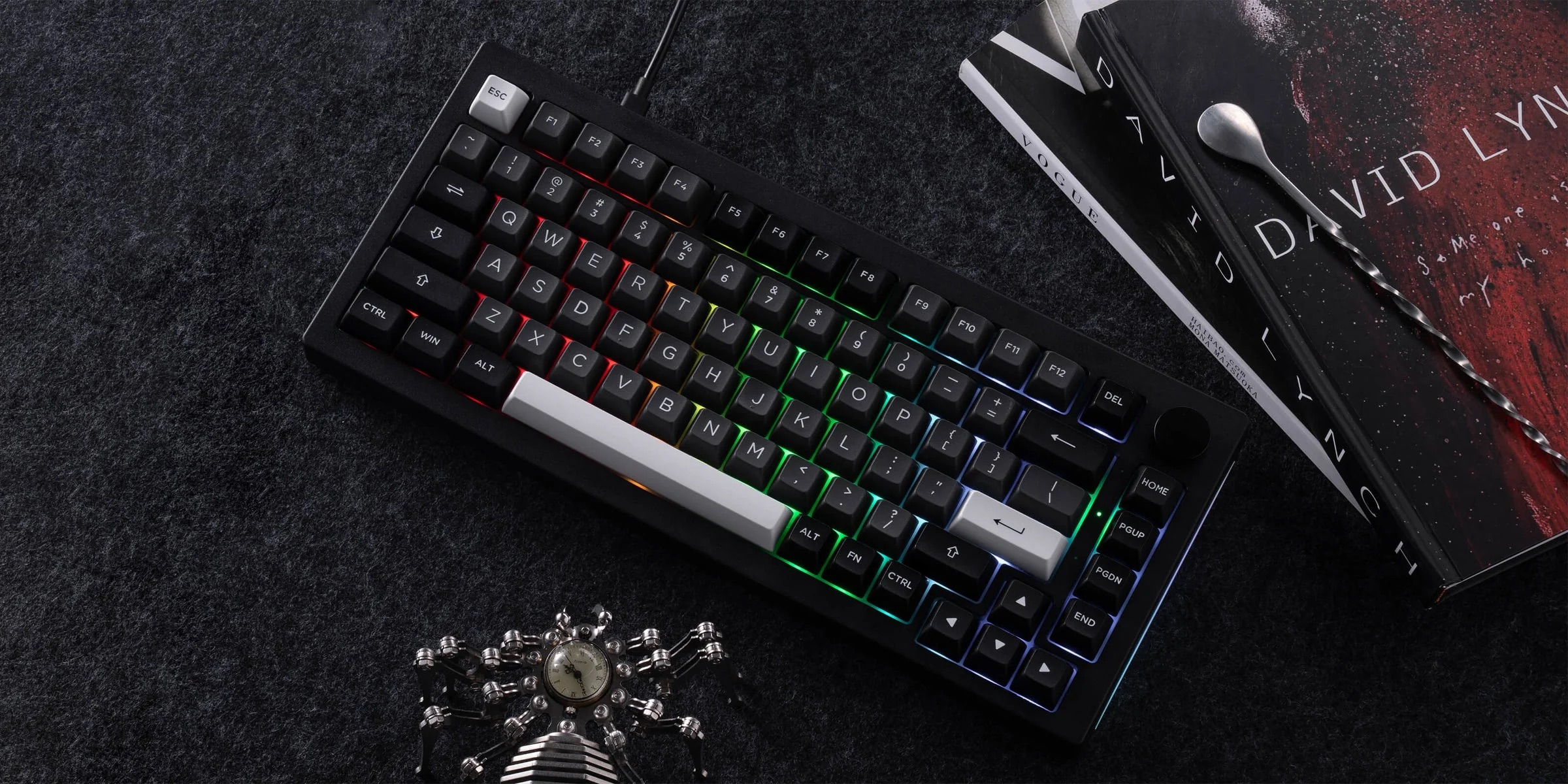 Czarna klawiatura z podświetleniem RGB, obok książki i łyżka barmańska.