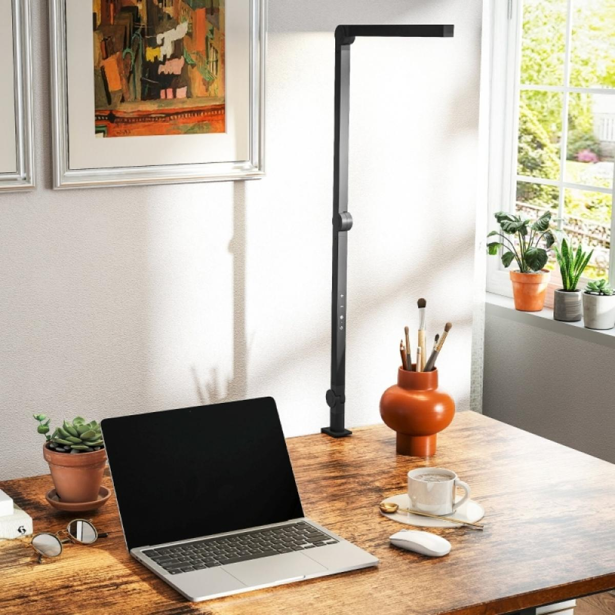 Ein Schreibtisch mit Laptop, Maus, Kaffeetasse, Topfpflanzen und einem Kunstwerk an der Wand.