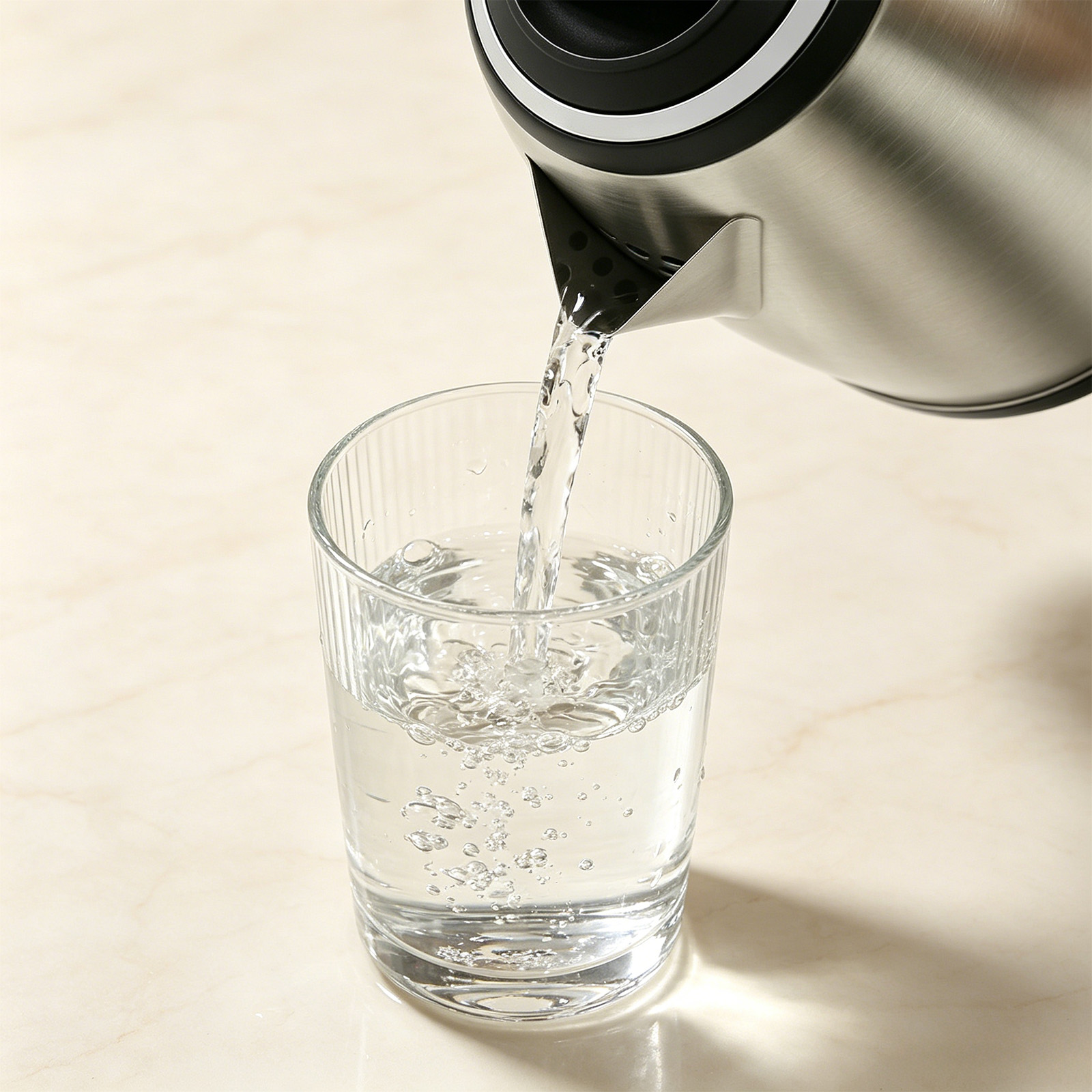 Wasser wird aus einem Metallkessel in ein Glas gegossen.