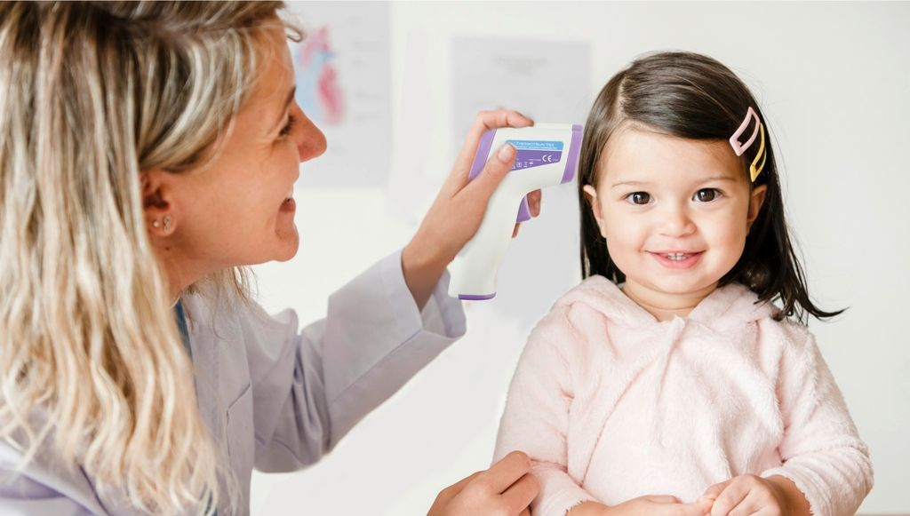 Arzt misst Fieber bei einem Kind mit einem digitalen Thermometer.