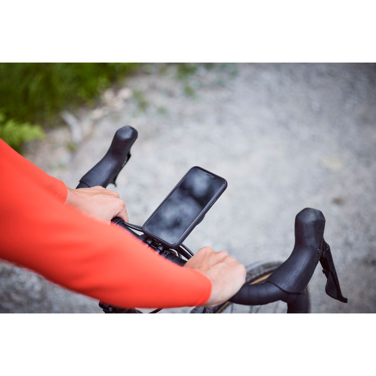 Manubrio bicicletta con supporto telefono, persona in maglia arancione tiene manubrio.