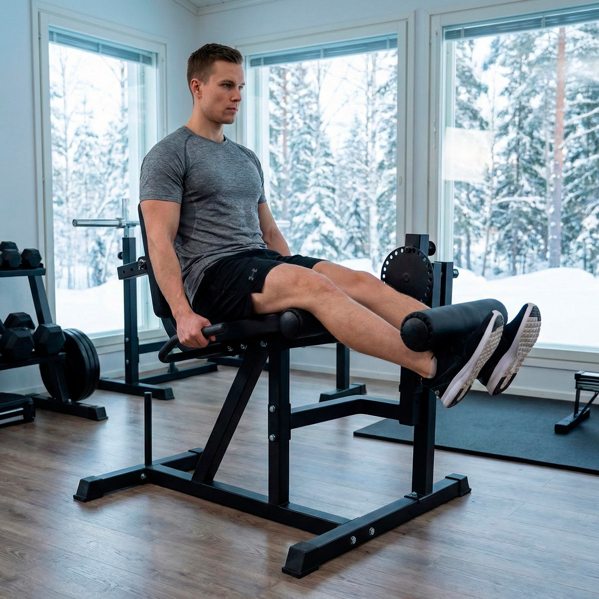 Ein Mann trainiert seine Beine an einem Fitnessgerät in einem Fitnessstudio mit Schneelandschaft draußen.