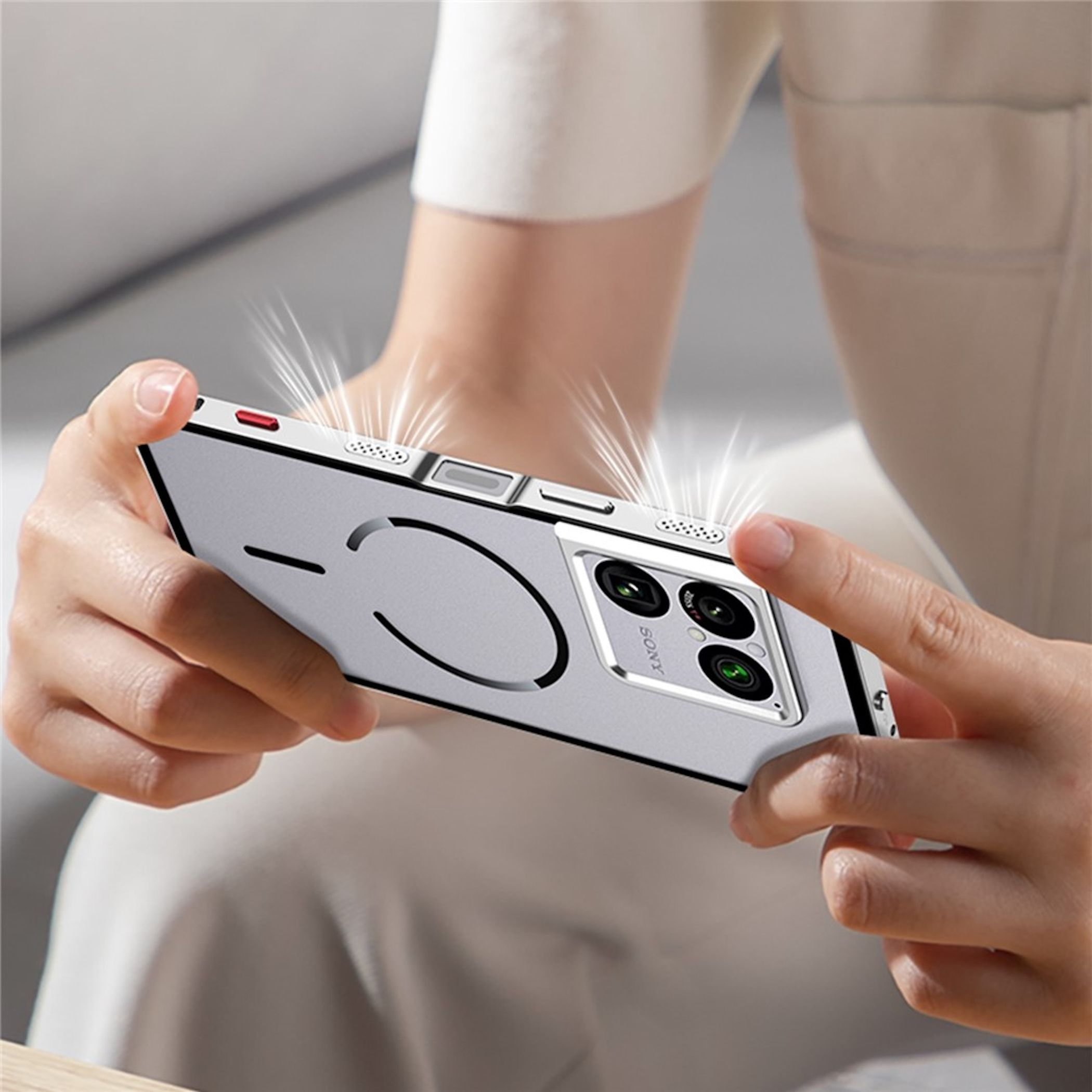 Eine Person hält ein silbernes Smartphone mit einem Kameraobjektiv.
