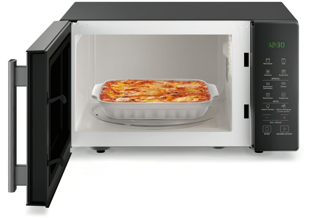 Ein offenes schwarzes Mikrowellengehäuse mit Lasagne in einer weißen Auflaufform.