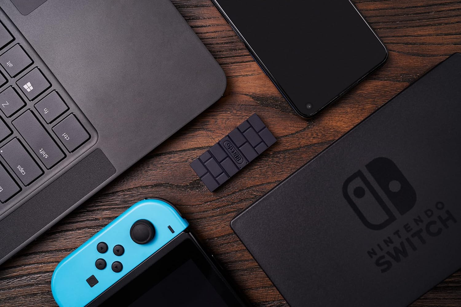 Ein Nintendo Switch, Laptop, Smartphone und ein USB-Stick auf Holz.