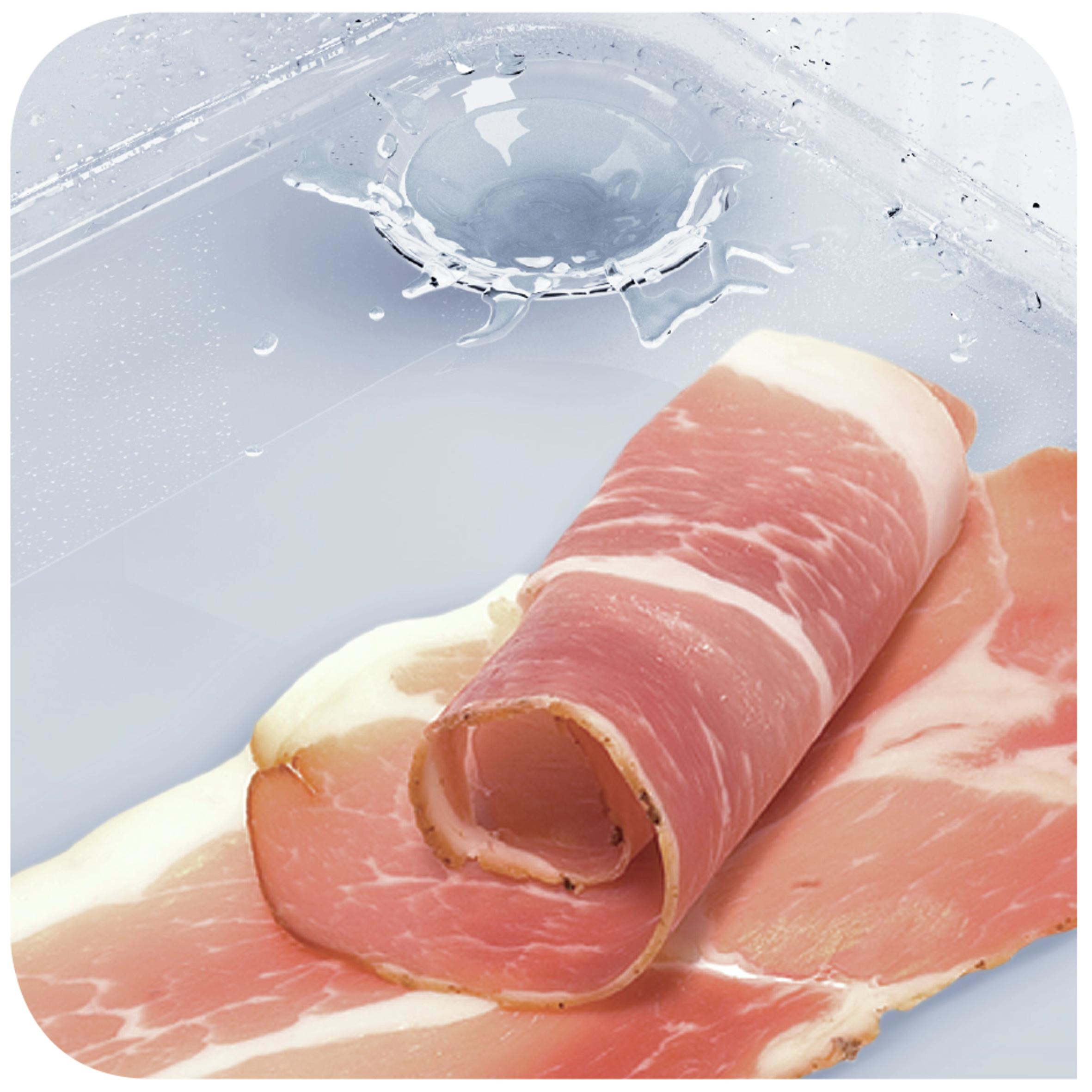 Dünne Scheiben Schinken mit Wasser und Spritzern im Hintergrund.