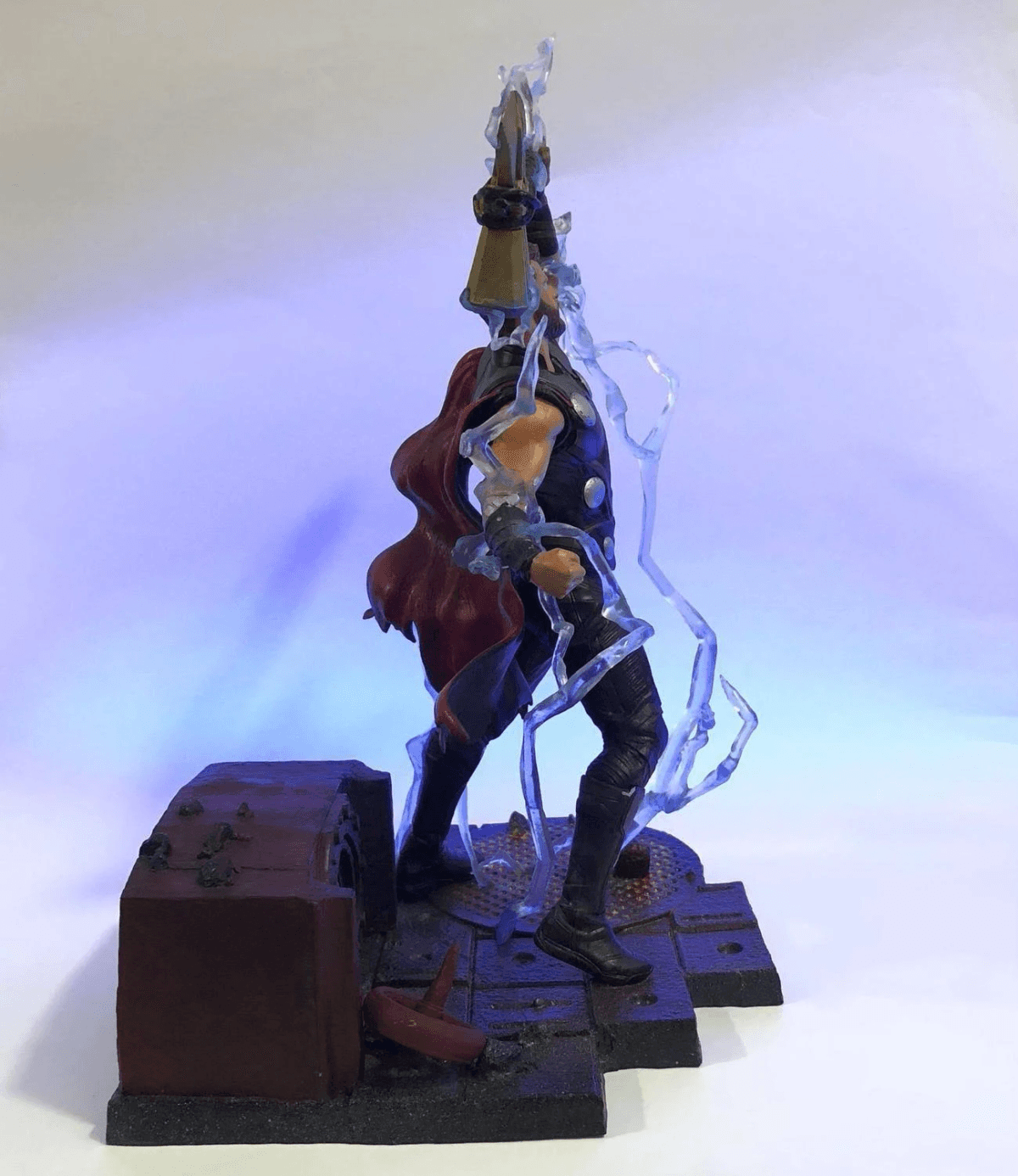 Figura de Thor con martillo y rayos sobre una base de piedra.