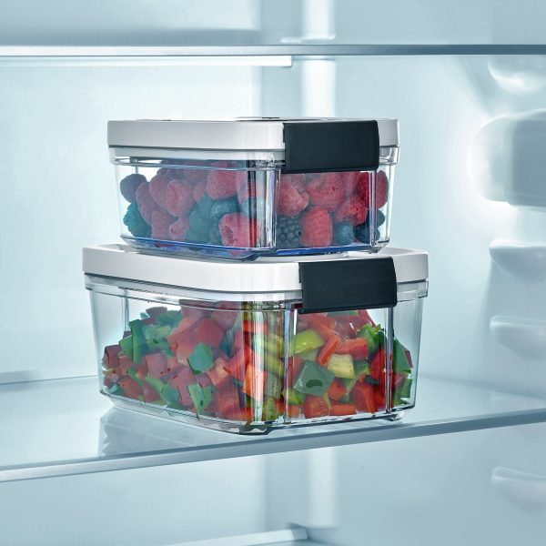 Zwei stapelbare Frischhaltedosen mit Beeren und geschnittenem Gemüse in einem Kühlschrank.