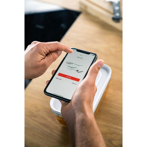 Persona usa smartphone sopra contenitore cibo, cucina.