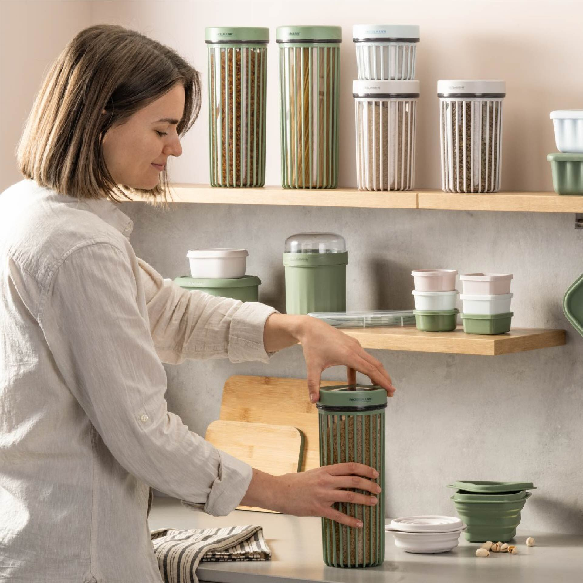 Une femme attrape un pot à pâtes vert, d'autres pots sont à proximité sur des étagères.