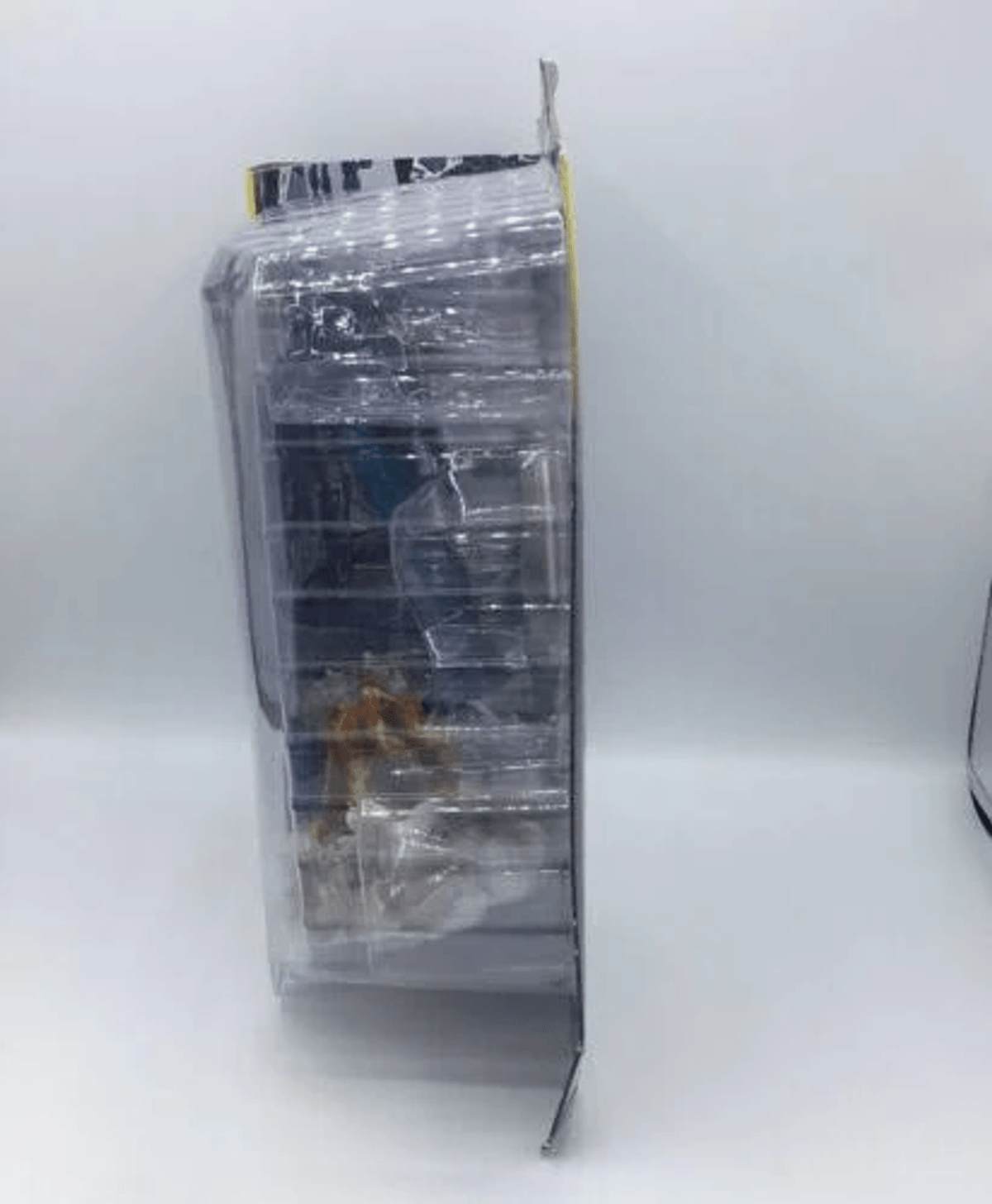 Un juguete en un empaque transparente, de pie sobre una superficie blanca.
