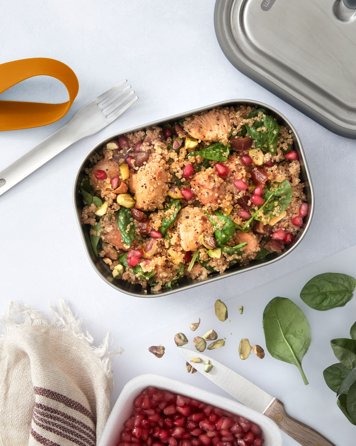 Quinoa-Salat mit Hähnchen, Granatapfelkernen und Pistazien in einer Metallbox.