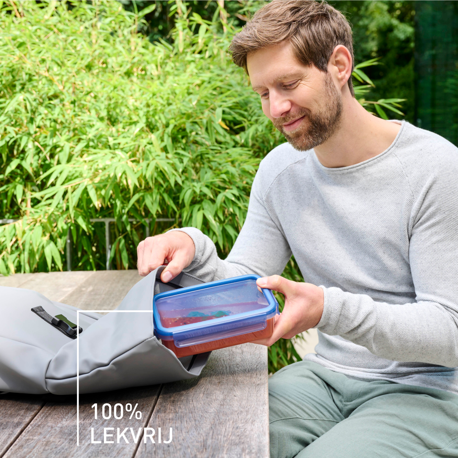 Uomo che mette un contenitore trasparente con coperchio blu in una borsa grigia.