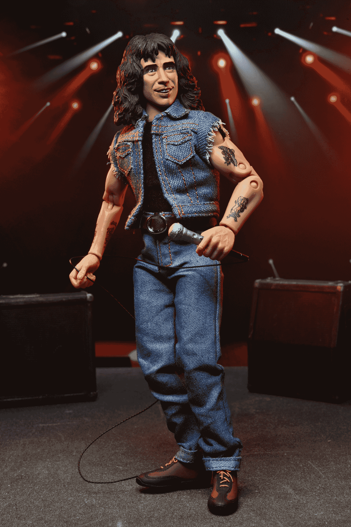 Un cantante de figura de acción con micrófono y atuendo vaquero en un escenario.