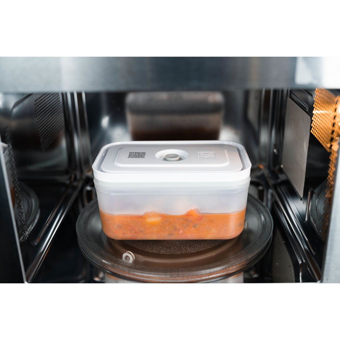 Un recipiente transparente con comida naranja dentro de un microondas.