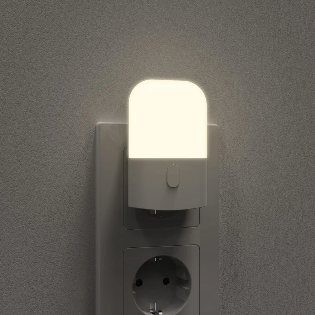 Una piccola luce notturna bianca brilla in una presa a muro su una parete grigia.