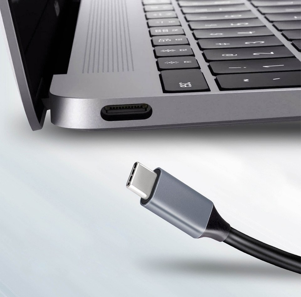 Ein USB-C-Kabelanschluss nähert sich einem Laptop-Anschluss.