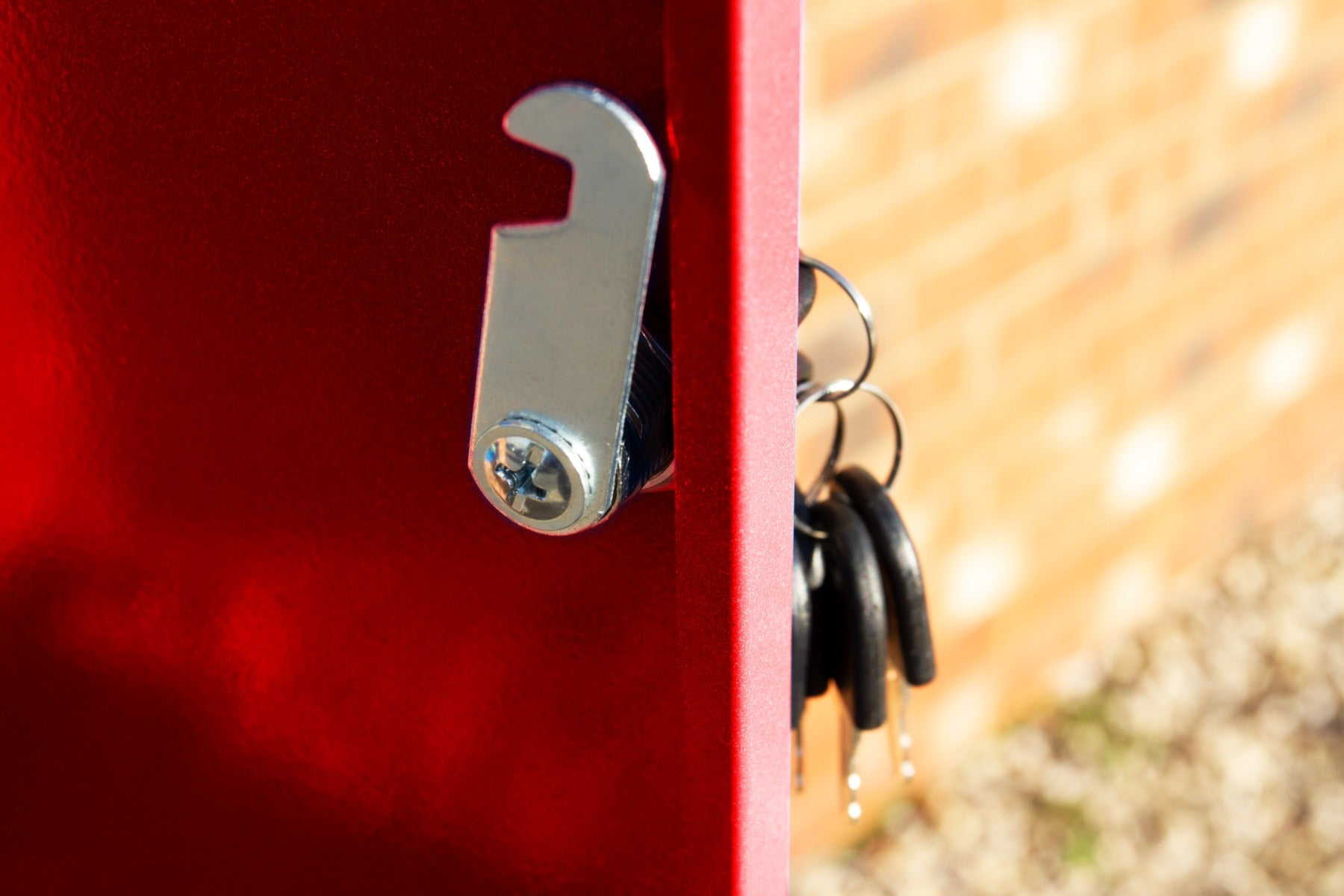 Un recinto de metal rojo con una cerradura plateada y llaves al fondo.